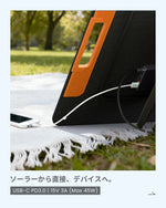 Close-up of a smartphone directly fast-charging from the ZOUPW 220W solar panel via the 45W USB-C PD3.0 port on grass.